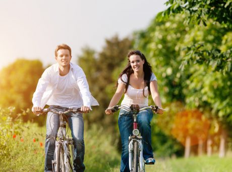Happy young couple cycling with bicycle in summer in nature, man and woman
