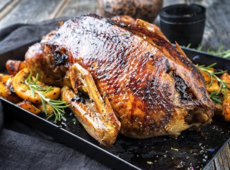 Traditional roasted Christmas goose with fruits and potatoes as closeup on a board